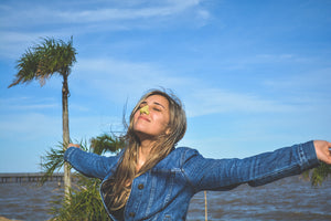 Young woman enjoying the breeze while wearing colorful sunscreen on her nose